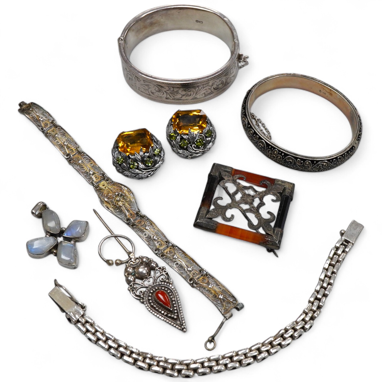 A group of silver jewels, comprising: a Scottish hardstone brooch of square outline; a pair of Arts and Crafts citrine and green tourmaline ear clips, length 2.7cm each; a silver link bracelet; a silver filigree bracelet